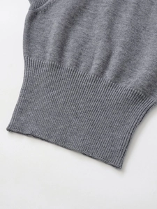 Detailed macro view of the grey knit sweater's ribbed cuff and premium fine texture