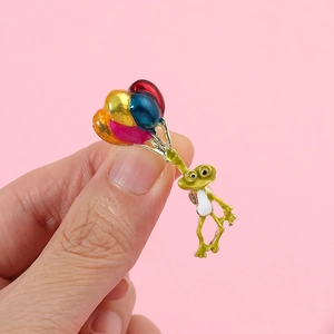 Détail de la broche grenouille en émail tenant quatre ballons colorés créatifs
