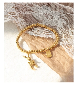 Makro-Detail des goldenen Perlenarmbandes mit Glückshasen-Anhänger und Markenlogo