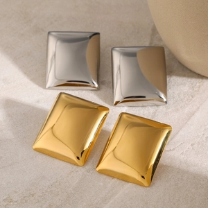 Detailed view of square geometric earrings in gold and silver mirror finish on stone