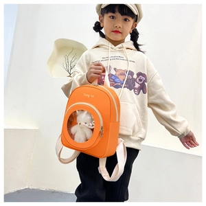 Detail of orange kids backpack with transparent window and cute white plush bear mascot