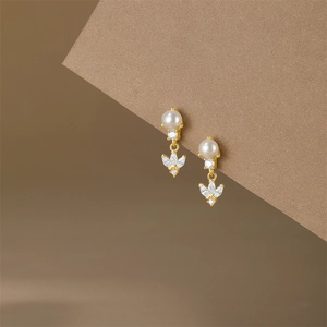Detailed view of elegant gold pearl earrings with shimmering zircon leaf pendants