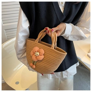 Detail of woven cotton rope tote bag featuring a large decorative pink floral charm