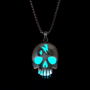 Close-up of glowing skull pendant with lightning bolt and blue luminous effect in dark