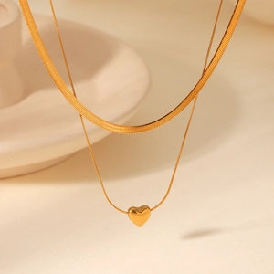 Détail d'un collier double rang doré avec maille serpent et pendentif en cœur