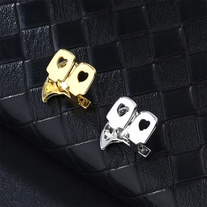 Macro shot of bird-shaped gold and silver hip hop grillz with heart cutout details