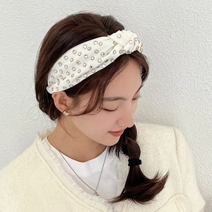 Detail of white knotted headband for women featuring shimmering rhinestones and soft satin