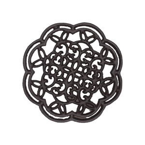 Rustic round cast iron trivet with intricate owl hollow pattern on white background