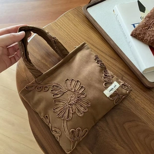 Detailed embroidery of floral patterns on camel suede tote bag with simple wish label