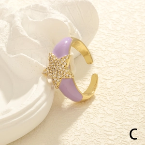 Detail of adjustable gold ring with purple enamel finish and a sparkling zircon star charm