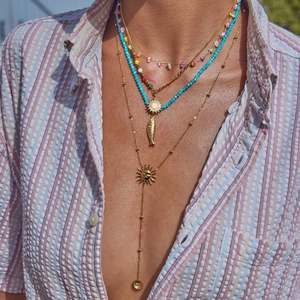 Bohemian multilayer gold necklace with turquoise beads and sun fish charms on model