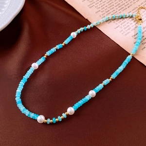 Detailed view of beaded necklace with freshwater pearls and blue stones on silk fabric