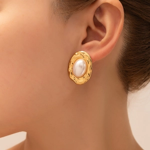 Detailed view of vintage gold flower earrings with hammered texture and large pearl
