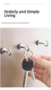Detail of brushed stainless steel magnetic hook holding keys on a beige wall