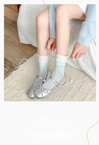 Detail of silver Mary Jane shoes with bow decoration and jacquard knit socks on feet