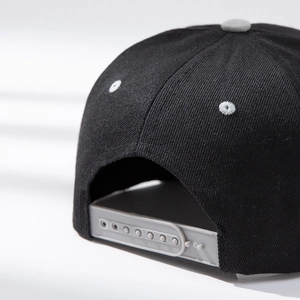 Detail shot of black cotton baseball cap with adjustable grey snapback closure and stitching
