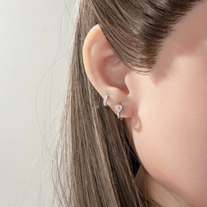 Pink heart crystal charms on silver hoop earrings worn by a model in a close-up shot