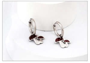 Detailed close-up of mushroom dangle earrings with red enamel and white polka dots