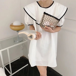 Close-up of a white heart pattern mesh pouch held by a model in a minimal dress