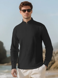 Detail view of a men's black linen shirt with a mandarin collar on a beach backdrop