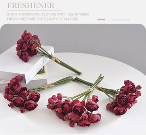 Top view of four dark red artificial rose bouquets on a minimalist white table surface