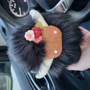 Close-up of fluffy Highland cow doll ornament featuring faux fur and floral details