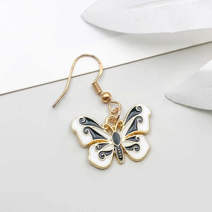 Macro detail of gold-framed butterfly earring with black and white enamel finish