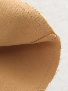 Gros plan des coutures internes d'une veste en daim kaki avec texture de toile