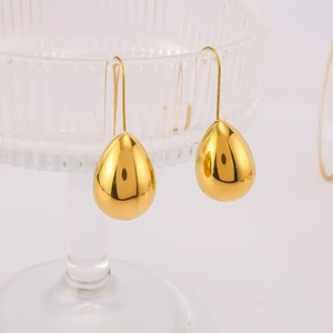Elegant gold drop earrings on a glass rim with high-gloss polished stainless steel finish