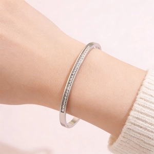 Macro detail of silver-toned stainless steel bangle with pavé crystals on a woman's wrist