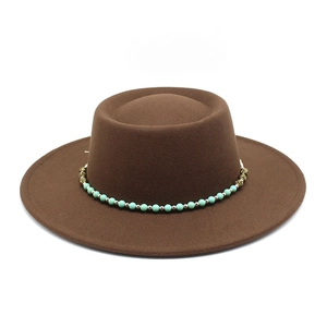 Close-up of brown wool flat top hat featuring turquoise beads and gold metal chain