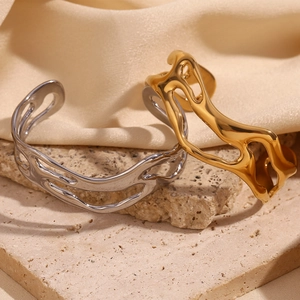Artistic gold and silver hollow wavy bangles displayed on stone with silk background