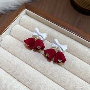 Detail of red velvet Christmas bell earrings with white bow and gold pearl accents