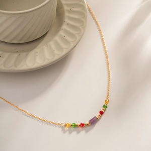 Elegant gold stainless steel necklace with vibrant colorful crystal beads on white surface