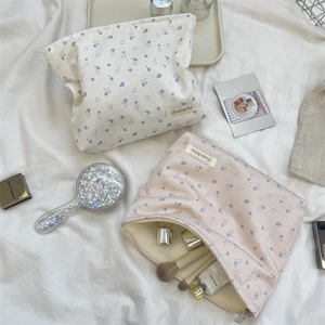 Close-up of floral makeup bags in cream and pink colors with functional metal zippers