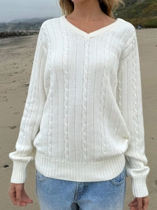 Detail of white V-neck cable knit sweater with ribbed texture worn in beach setting