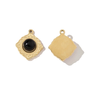 Macro view of square gold plated pendant with black stone and engraved detail