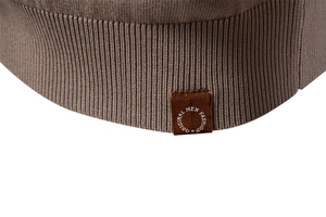 Macro view of ribbed knit hem and brown leather label on a khaki men's polo shirt