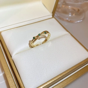 Detailed close-up of golden open ring with green stones in a velvet jewelry box