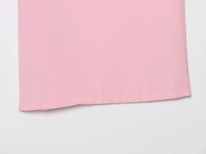 Gros plan détaillé des coutures et de l'ourlet en tissu rose sur une chemise ample