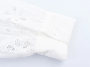 Detail of white shirt sleeve featuring delicate floral embroidery and buttoned cuff