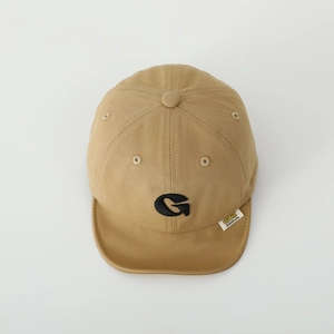 Detailed close-up of khaki cotton baby cap featuring black G embroidery and brand label