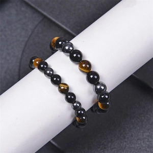 Beaded tiger eye and black obsidian stone bracelets on a white jewelry display stand