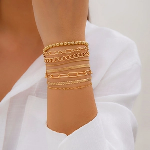 Close-up of a layered gold heart pendant bracelet set featuring beaded and paperclip chains