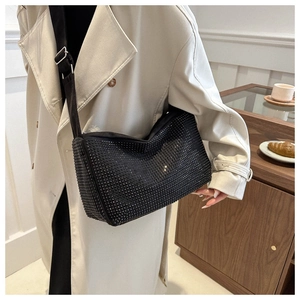 Détail du sac bandoulière noir à strass avec large sangle sur mannequin dans un intérieur cosy