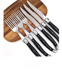 Detail view of 6-piece stainless steel cutlery set with black ergonomic handles on wood