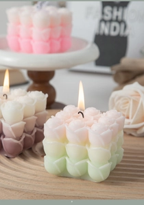 Detailed view of burning rose-shaped scented candles in gradient pink and green colors