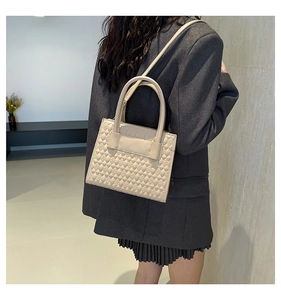 Detail of quilted rhombic pattern on off-white faux leather handbag for women