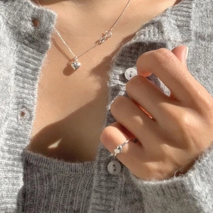 Macro shot of minimalist 925 sterling silver heart ring and necklace set on model