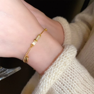 Close-up of gold-plated bamboo joint bracelet with zircons worn on wrist with sweater